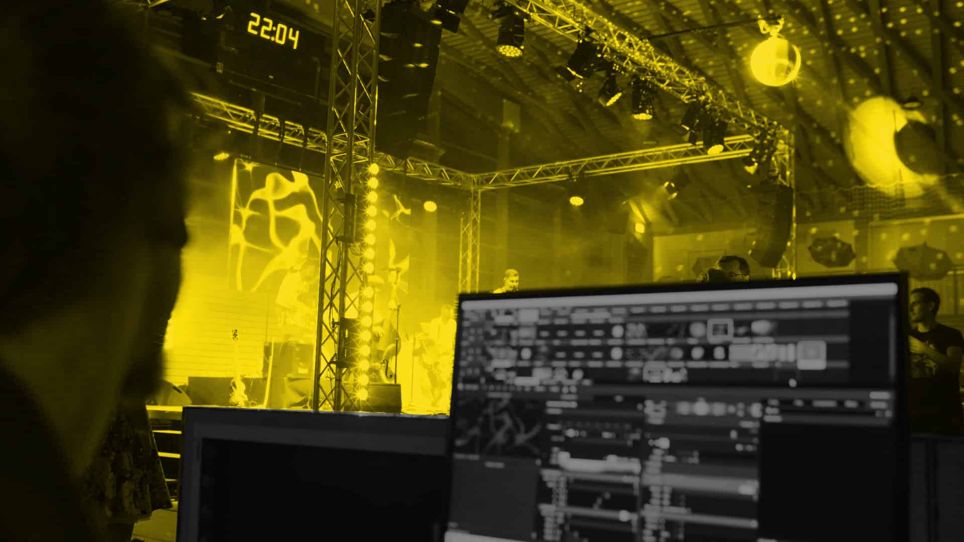 eine Lichtkonsole steht in der Regie vor einer Bühne mit einer Band